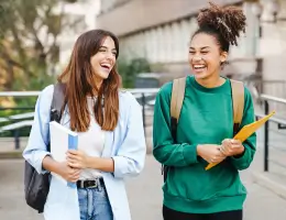 two women holding notebooks and walking outside